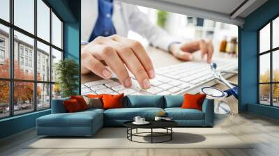 Female doctor typing on computer Wall mural