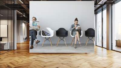 Man reading newspaper and woman using digital tablet Wall mural