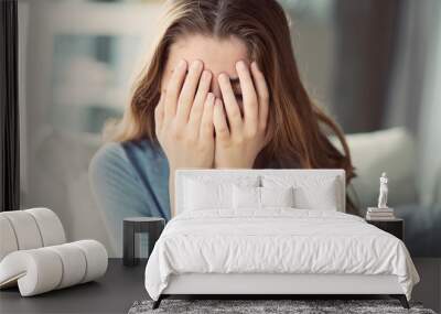 Sad young woman covered her face with her hands Wall mural