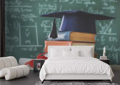 Stack books  graduate hat and diploma in front of  green chalkboard Wall mural