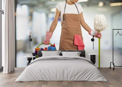 Young woman with cleaning supplies in building Wall mural