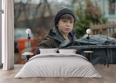 Young Boy Taking Out the Trash on a Cold Day with a Focused Expression Wall mural