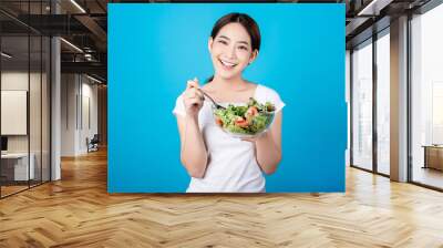 Beautiful young asian eating salad with big smile happy beaming face in seamless blue isolated background. Diet healthy concept. Her face and skin are healthy, fresh, bright and youthful. Wall mural