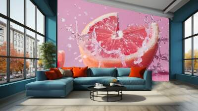 A grapefruit cut in half, with its pink flesh and a splash of juice  Wall mural