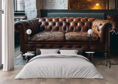 A vintage leather chesterfield sofa in a rustic setting, with wooden floors and warm lighting Wall mural