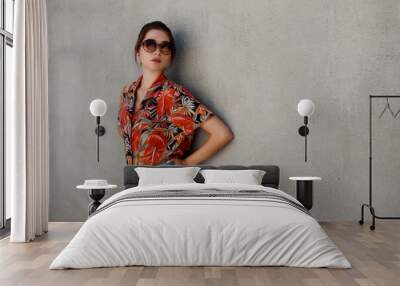 Pretty young slim asian woman in sunglasses and shirt over grey wall background Wall mural