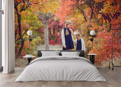 Two cheerful sisters playing in the park in warm autumn day Wall mural