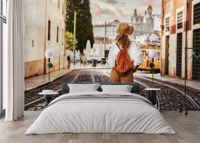 Young tourist traveling through beautiful sunny european city and looking at view, rear view Wall mural