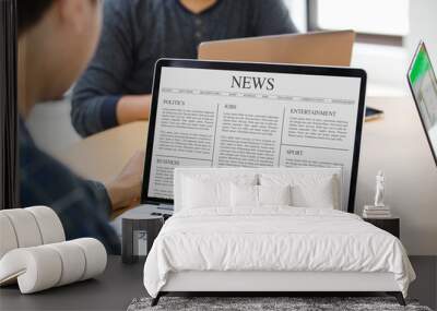 Man reading news article on the laptop screen at office Wall mural