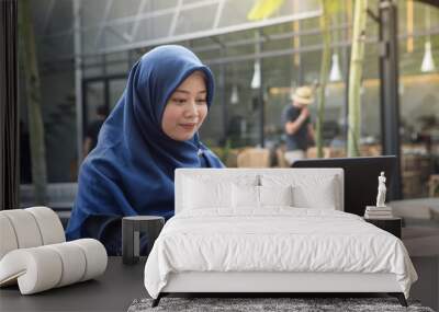 southeast asian muslim women with hijab using laptop at the outdoor cafe Wall mural