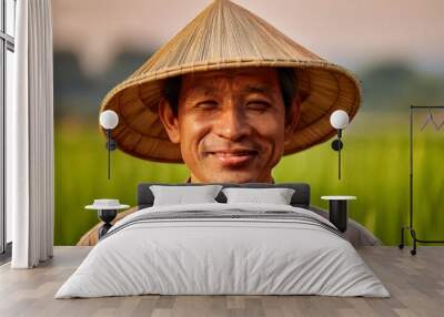 Portrait of a middle-aged male farmer smiling, wearing a straw hat in an agricultural setting. The blurred background shows a field, depicting a hardworking and reliable farming professional. Wall mural