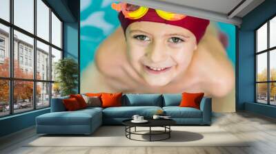 Portrait of a smiling child with a red swimming cap and water goggles. Wall mural