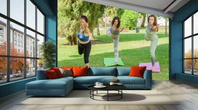 Three women doing the yoga posture of the dancer. Wall mural