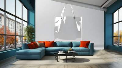 A transparent plastic shopping bag is displayed on a plain grey background, showcasing its simplicity and practicality Wall mural