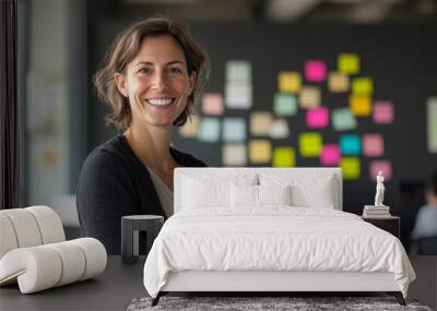 A happy business woman stands in front of her team in the office. Wall mural