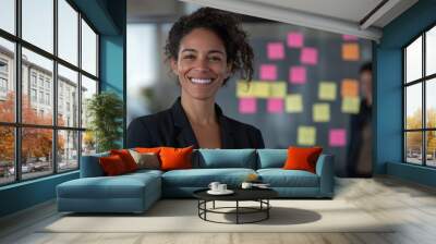 A happy business woman stands in front of her team in the office. Wall mural