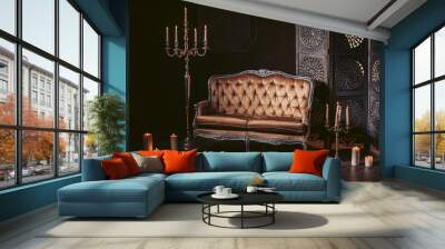 A luxurious sofa made of golden fabric in a modern interior decorated with decor and candles. In dark colors. Wall mural