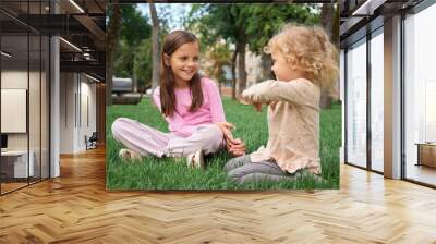 Caucasian siblings playing together in green park on lawn with sunlight and joy during outdoor adventure happy girls in nature together with cheerful smiles during summer afternoon Wall mural