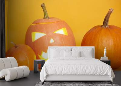 Halloween pumpkins isolated over yellow background, traditional spooky jack o lantern, american autumn holiday, three orange pumpkins against studio wall, last October night. Halloween concept. Wall mural