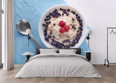 Image of bowl of oatmeal porridge with blueberries and raspberries on white wooden table, tasty english brekfast, delicious meal for healthy eater isolated on white. Halthy eating and diet concept. Wall mural