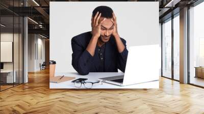 Overworked tired stressful male keeps hands on head, lools with puzzlement, doesnt know how to prepare financial report, wears formal clothes, focused into portable laptop computer, writes notes Wall mural