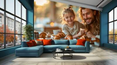 A happy family sitting together at the breakfast table and eating fresh croissants. Wall mural