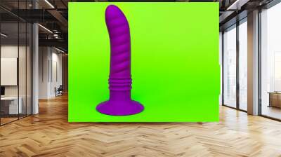 A purple dildo on a green background Wall mural