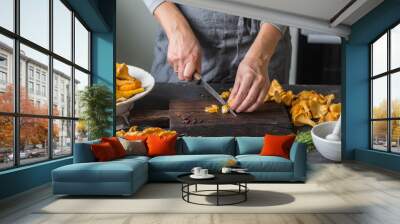 Woman is cutting fresh chanterelles on the boards in the kitchen Wall mural