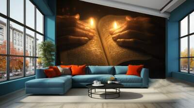 Two hands hold a book open by candlelight. Wall mural