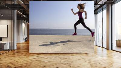 Young beautiful girl jogging and training on the beach Wall mural