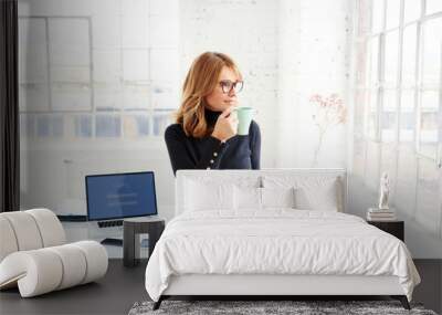 Beautiful businesswoman standing in the office while drinking her coffee Wall mural