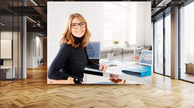 Confident businesswoman wearing casual clothes while sitting at office and working Wall mural