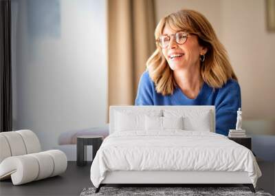 Cropped shot of a middle-aged woman with blonde hair relaxing in an armchair at home Wall mural