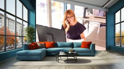 Executive businesswoman talking on mobile phone while working in the office Wall mural