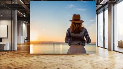 Rear view of woman standing on the balcony and enjoying the sea view Wall mural