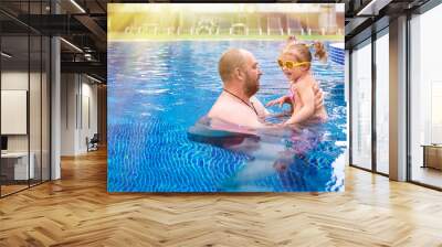 Dad teaches a little daughter to swim in the pool. Wall mural