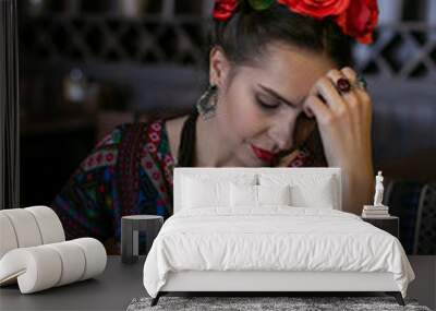 vertical photo of a young woman in mexican national dress who is sitting at a table with a glass of wine Wall mural