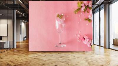 Creative composition of pink flowers and wine glass pink background. Flowerscape flat lay. Copy space Wall mural