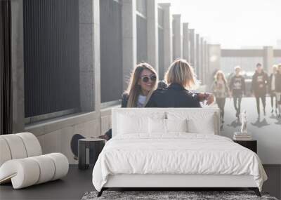 Two girl friends having fun together with skateboard. Outdoors, urban lifestyle. Wall mural