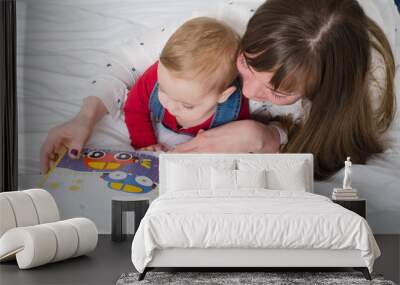 Little boy with her mother reading a book in bed Wall mural