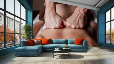 Male masseur doing back massage to client woman in dark room of massage spa Wall mural