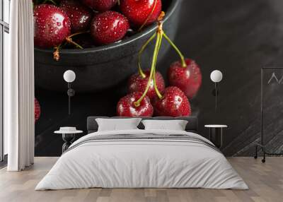 Fresh sweet cherries with water drops in bowl on dark rock table. Wall mural