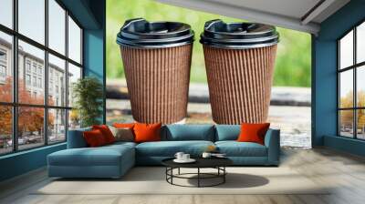 Two cups with hot drink to take away in park on wooden bench. Close-up view of two disposable coffee to go cups. Romantic date with coffee. Takeaway Business meeting. Nice conversation over cup of tea Wall mural