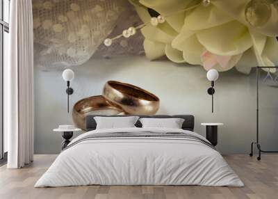 Two wedding rings lie on a light horizontal surface against a bo Wall mural