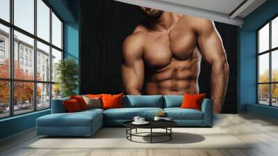 Brutal sexy man with six pack abs in towel at black background. Handsome fitness male model sitting in studio. Bearded muscled guy covering with towel in studio. Wall mural