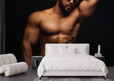 Latino hunk in white swimwear at black background in studio Wall mural