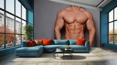 Studio portrait of shirtless male model in pink shorts at grey background Wall mural