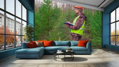 A forest ecologist oversees the development of a young forest. Real people work. Wall mural