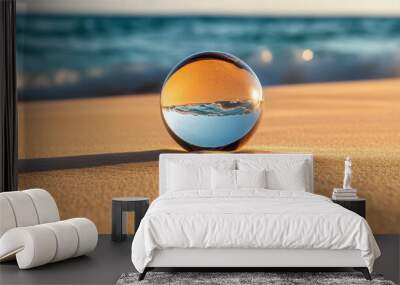 A glass ball is sitting on the sand at the beach Wall mural