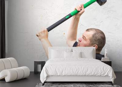 A man is holding a hammer and swinging it at a wall Wall mural